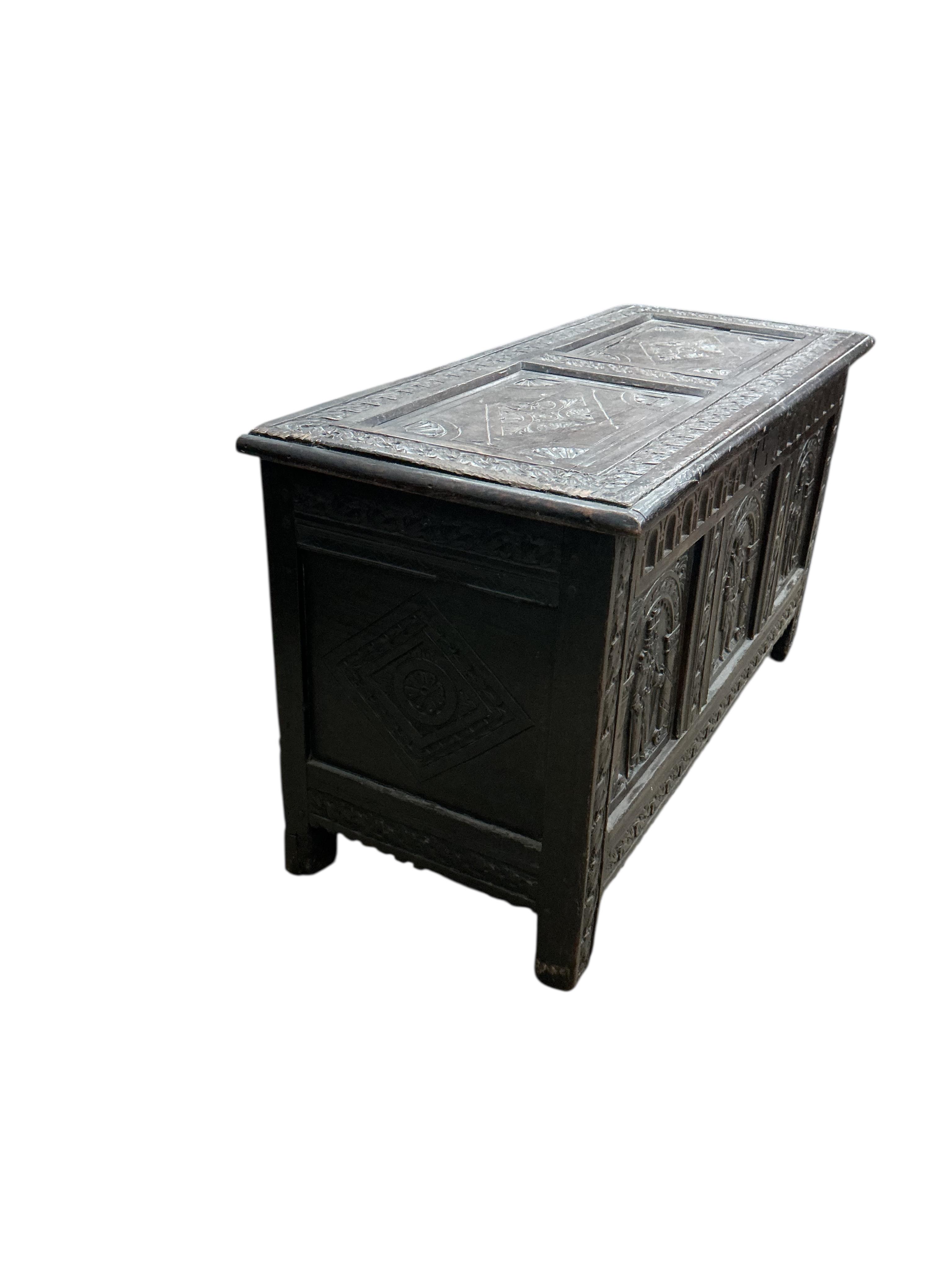 An 18th century oak panelled coffer, later carved, width 116cm, depth 49cm, height 64cm